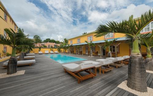 a resort with a pool and lounge chairs and palm trees at Wanna Studio Apartments in Pointe aux Cannoniers