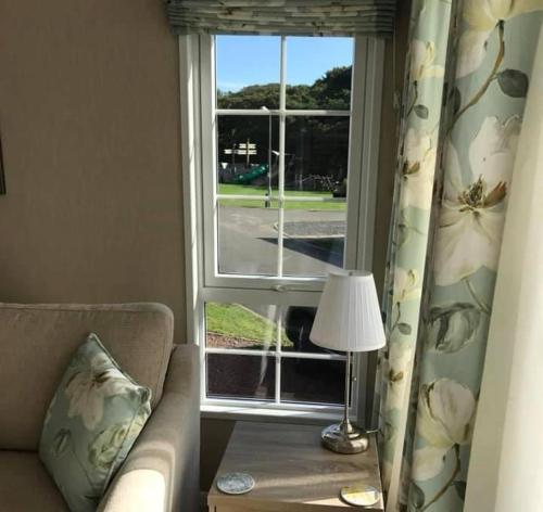 a living room with a window with a couch and a lamp at Lemon Tree Lodge in Morpeth