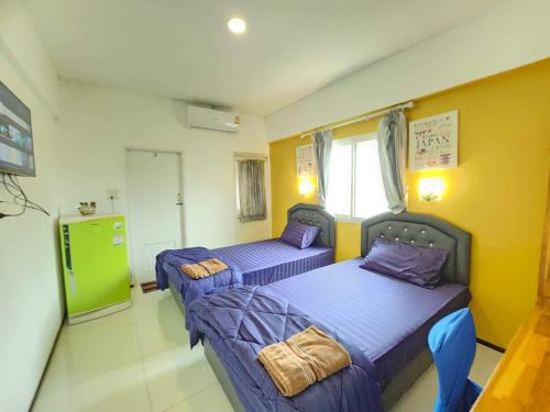 two beds in a room with yellow walls at Psm at Donmueng in Ban Don Muang