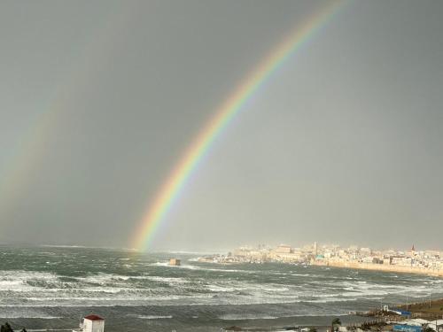 a rainbow over the ocean with a city at Acre sea view 11th floor apartment in ‘Akko
