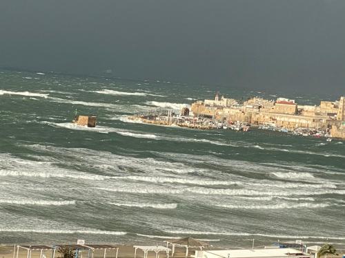 a view of the ocean with a city and buildings at Acre sea view 11th floor apartment in ‘Akko