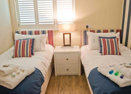 1 Schlafzimmer mit 2 Betten mit Kissen und einem Nachttisch in der Unterkunft The Sherwood Hideaway Lodges 