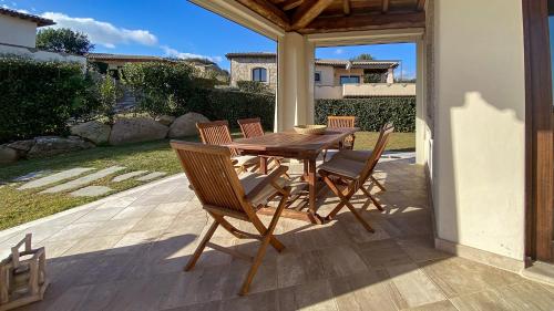 una mesa de madera y sillas en un patio en Villa Dalia Punta Molara San Teodoro en San Teodoro