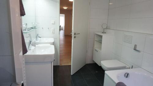 La salle de bains blanche est pourvue d'un lavabo et de toilettes. dans l'établissement Ferienwohnung XL Komfort 8B, à Daisendorf