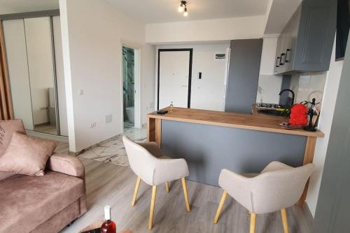 a living room with a couch and a kitchen with white chairs at 1 apartament lux cu parcare privată gratuită in Iaşi