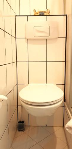 a white toilet in a white tiled bathroom at Villa Hoffnung in Bad Elster