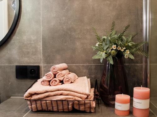 a bathroom with a basket of towels and a vase of flowers at Apartament Comfy in Nowy Sącz