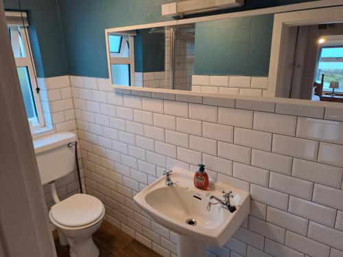 a bathroom with a sink and a toilet and a mirror at Blaneys Coastal Cottage in Mountcharles