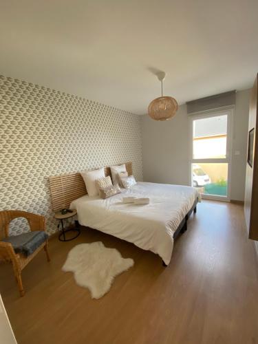 ein Schlafzimmer mit einem großen Bett und einem Stuhl in der Unterkunft Les embruns in Saint-Quay-Portrieux