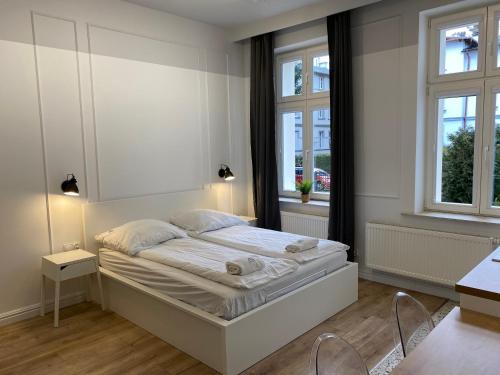 a bedroom with a large bed with two windows at RJ Family Sopot in Sopot