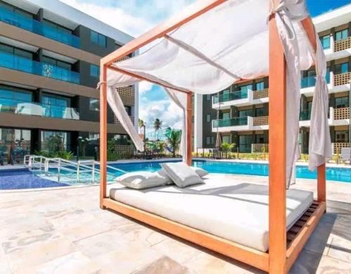 a bed in front of a swimming pool at Flat luxo no Mana Beach em Muro Alto 4 pessoas in Porto De Galinhas