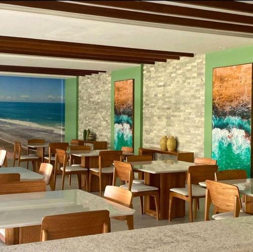 a restaurant with tables and chairs and the ocean at Flat luxo no Mana Beach em Muro Alto 4 pessoas in Porto De Galinhas