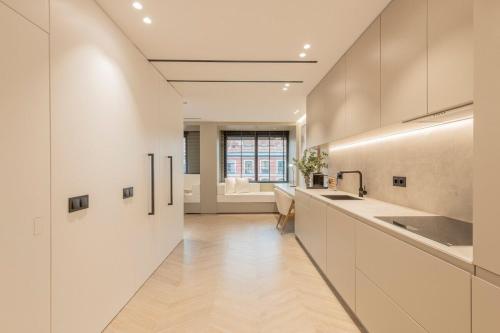 a kitchen with white cabinets and a long hallway at MyHouseSpain - Luminoso piso en Chamberí in Madrid