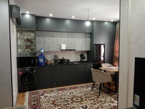 una cocina con armarios negros, lavadora y secadora en apartment seven A, en Tashkent
