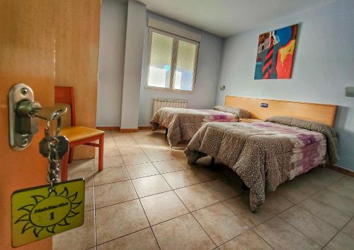 um quarto com duas camas e uma mesa e uma janela em Hostería Sol em San Miguel de Meruelo
