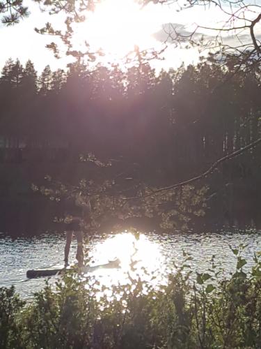a person is standing on a paddle board in the water at Villa Uuttu in Kuusamo