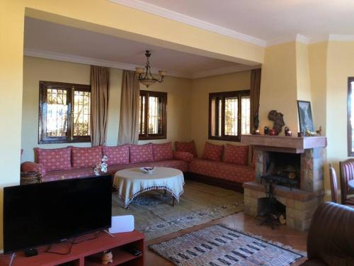 a living room with a red couch and a fireplace at Welcome to Chalet B. in Ifrane