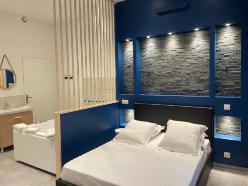 - une chambre avec un mur bleu, un lit et une baignoire dans l'établissement Les Bulles de Mona "Le 149" -PROXIMITE GARE DE LYON-, à Lyon