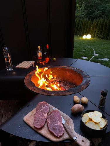 a table with a grill with meat and a fire at KONTAINERLOFT in Laz