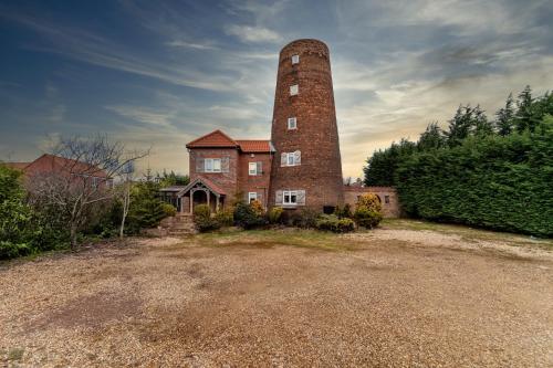 an old brick building with a tall tower at The Windmill by TJ Serviced Property in Farcet