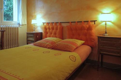 a bedroom with a bed with an orange headboard and two lamps at Gîte CAMPANULES - 5 personnes - "Les Gites du Chalet" à Autrans in Autrans