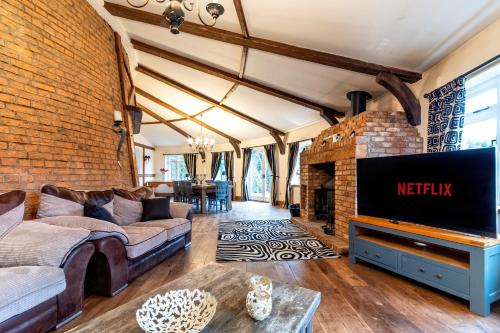 a living room with a brick wall and a tv at The Windmill by TJ Serviced Property in Farcet