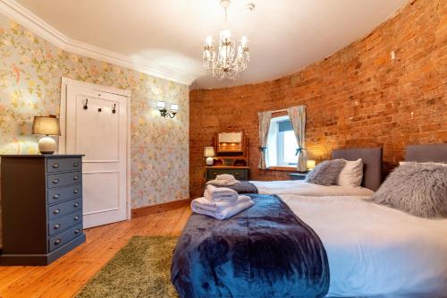 a bedroom with two beds and a brick wall at The Windmill by TJ Serviced Property 