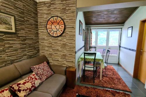 a living room with a couch and a table and a clock at H(a)ver as Faias in Manteigas