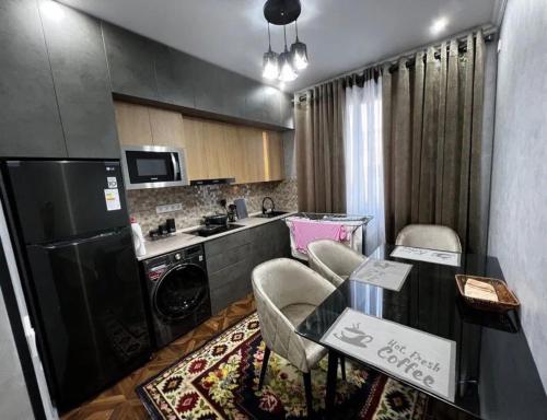 cocina con nevera negra, mesa y sillas en Apartment seven B, en Tashkent