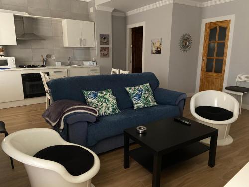 a living room with a blue couch and white chairs at Apartamento Venus in Salar