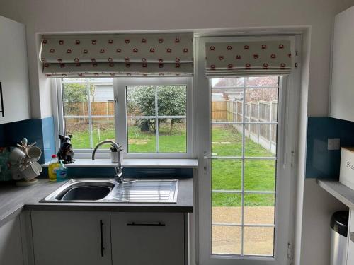 a kitchen with a sink and two windows at Klara's House in West Mersea