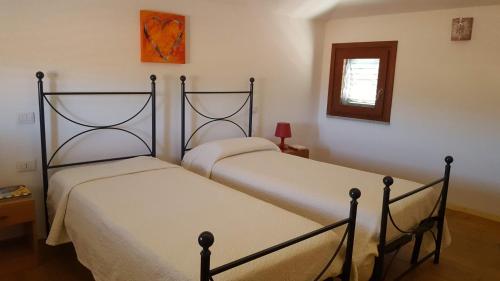 2 Einzelbetten in einem Schlafzimmer mit Fenster in der Unterkunft Casa Sant'Anna in Lotzorai