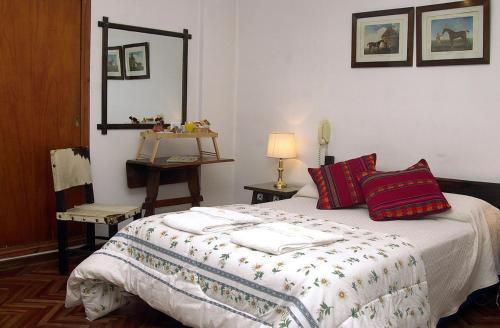 a bedroom with a bed with pillows and a mirror at Hotel Regidor in Salta