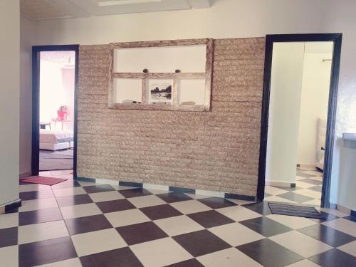 DerouaにあるVilla Proche de l'aéroport Mohammed Vの窓のある壁とチェッカーフロアの客室です。