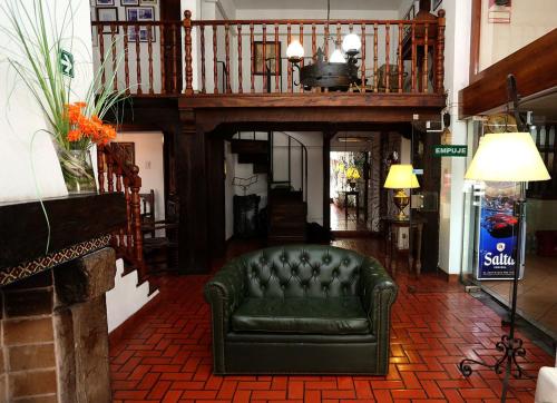 a living room with a green couch and a staircase at Hotel Regidor in Salta