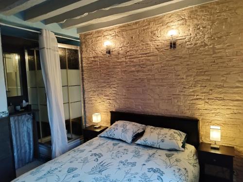 une chambre avec un lit et un mur de briques dans l'établissement Disney Appartement, à Quincy-Voisins