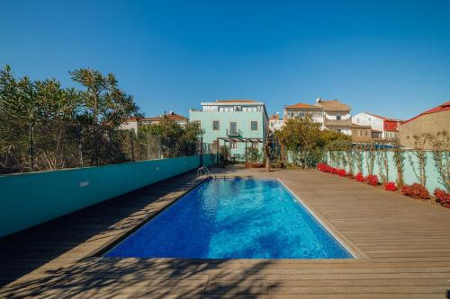 a swimming pool next to a wooden deck with a house at Oporto Pool Apartment by Vacationy in Porto