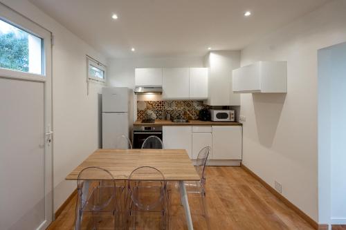 une cuisine avec des armoires blanches et une table et des chaises en bois dans l'établissement Maison Ohana 4-6 pers dans résidence Privée près de la Plage, à Canet