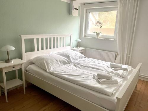Wohnung m. eigener Terrasse u. Zugang, Hamburg-nah في أرينسبورغ: سرير أبيض في غرفة نوم مع نافذة