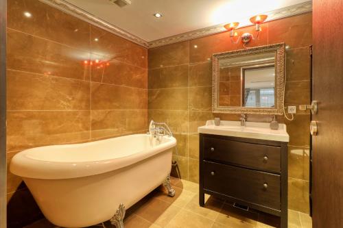 a bathroom with a tub and a sink and a mirror at Luxurious 3 Bedroom Apartment in Herastrau in Bucharest