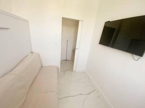 a white living room with a couch and a flat screen tv at Appartement 2P Idéalement Placé Juan les Pins in Juan-les-Pins