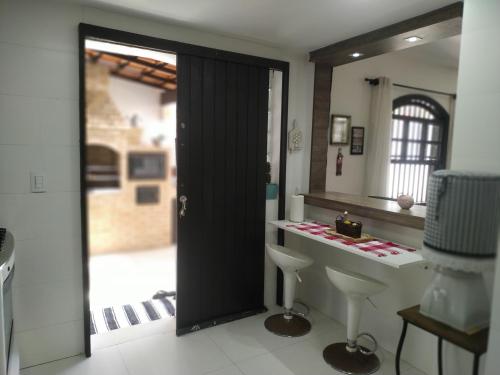La salle de bains est pourvue d'une porte noire et d'un comptoir blanc. dans l'établissement Casa em Cond Geriba 400mt Praia com Espaço Gourmet, à Búzios