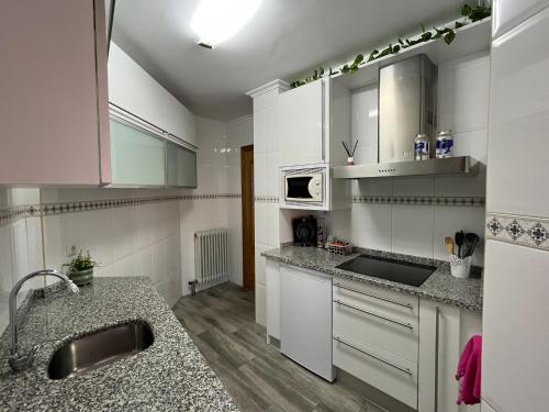 uma cozinha com armários brancos e bancadas em granito em Apartamento Palacio de Las Sevillanas em Haro