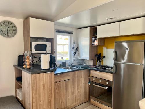 a kitchen with wooden cabinets and a stainless steel refrigerator at Mobile home Zen Siblu Fréjus in Fréjus