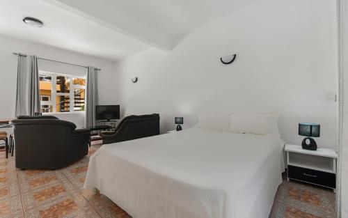 um quarto com uma grande cama branca e uma secretária em Wanna Studio Apartments em Pointe aux Cannoniers