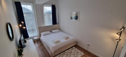 a small white bedroom with a bed and two windows at Apartament Calea Moldovei Residence - minibar si parcare GRATIS in Bistriţa