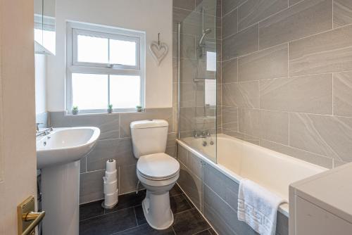 a bathroom with a toilet and a sink and a tub at 3 bedroom home sleeps 5 close to Chester City Centre welcomes couples, small groups, families and contractors in Chester