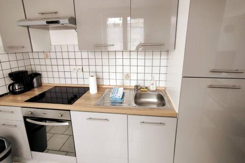 une petite cuisine blanche avec évier et cuisinière dans l'établissement Spacieux T2 proche tribunaux, à Douai