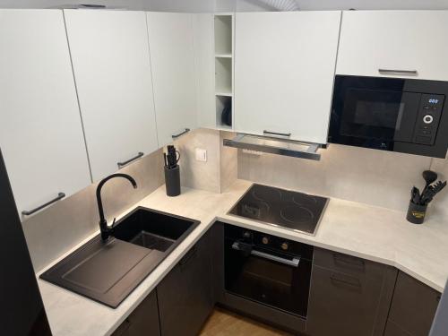 a kitchen with a sink and a stove and a microwave at Apartma Pohorske terase Brumen Mariborsko Pohorje in Hočko Pohorje