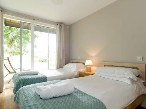 a bedroom with two beds and a large window at Cotswolds Lake side home with luxury spa Swallows Nest,Lower Mill Estate, Lakeside home/spa in Somerford Keynes